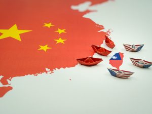 image-paper-boats-with-the-colors-of-the-usa-and-china-surrounding-the-island-of-taiwan-on-a-map